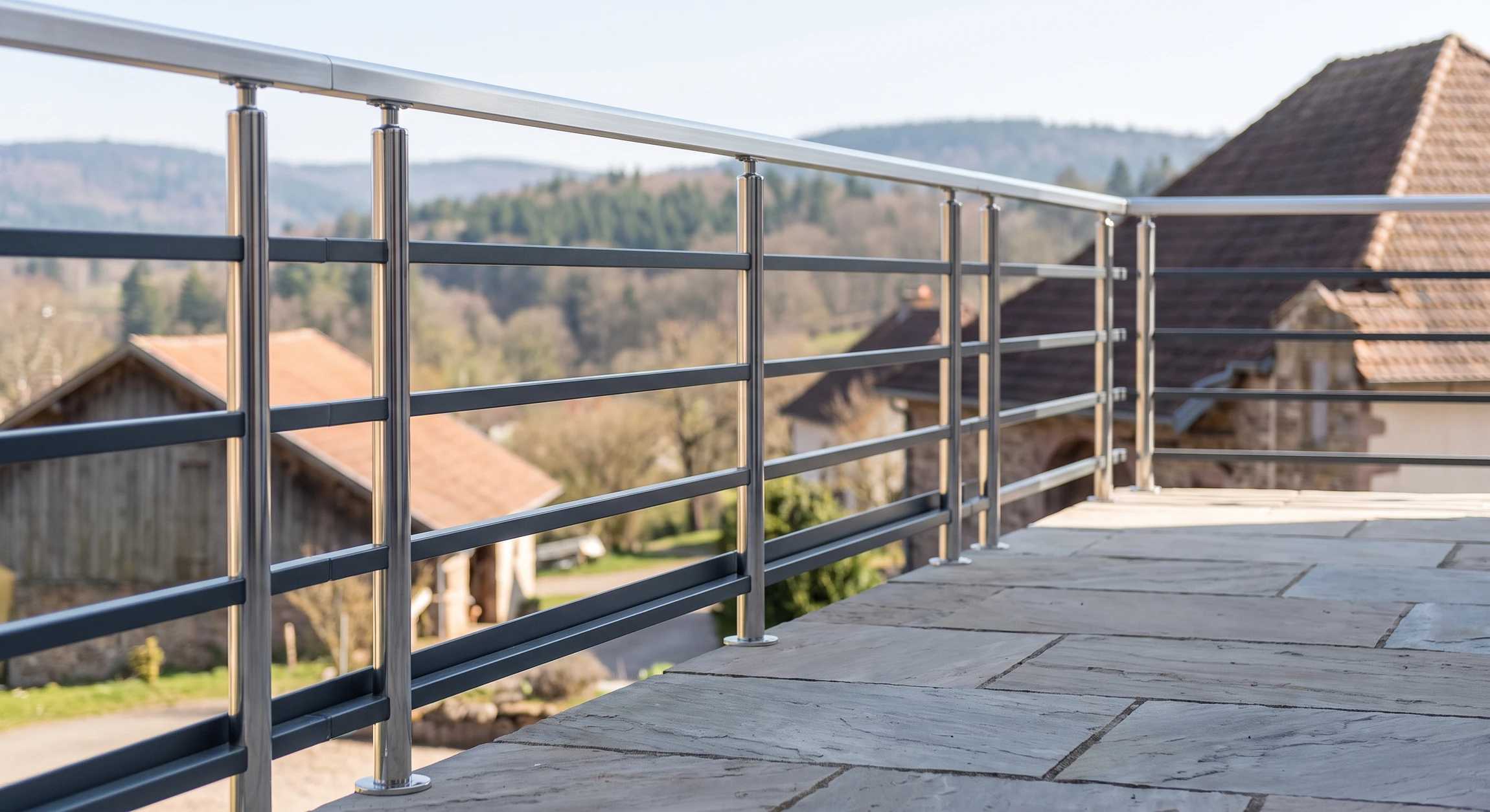 Garde-corps aluminium anthracite RAL 7016 installé en bordure de terrasse dallée, composé de poteaux verticaux chromés et lisse horizontale en profilé aluminium brossé, fixation encastrée, sécurité aux normes, menuiserie artisanale de qualité en situation réelle.