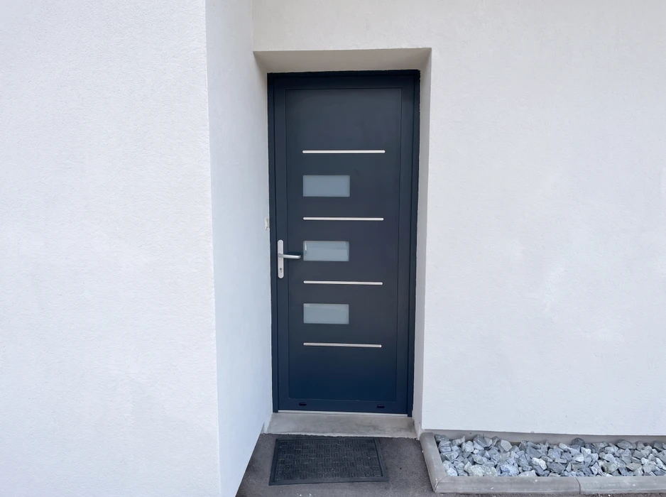 Porte d'entrée moderne anthracite installée en façade extérieure blanche