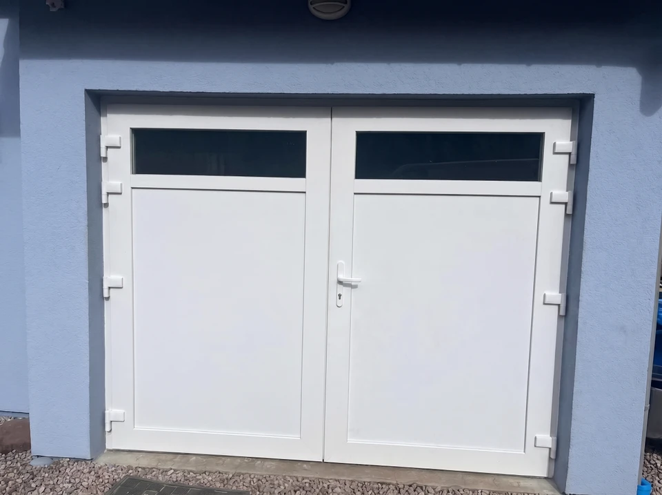 Façade extérieure d'un garage avec porte double battante en PVC blanc