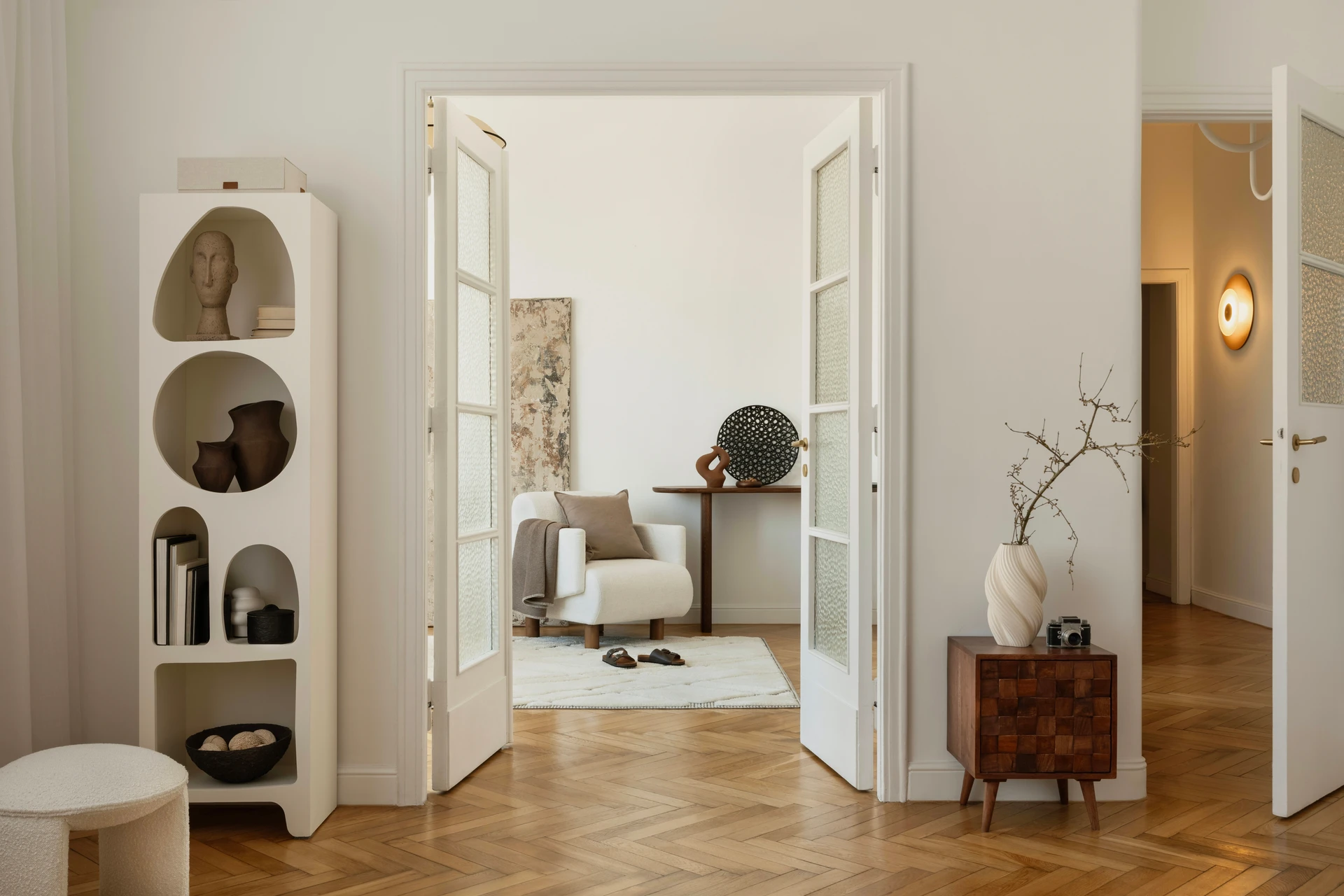 Artisan menuisier en salopette bleue installant une porte intérieure en bois clair avec inserts vitrés