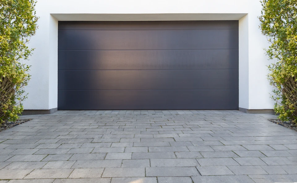 Façade extérieure d'une maison avec porte de garage sectionnelle en acier, coloris anthracite RAL 7016, à lames horizontales lisses